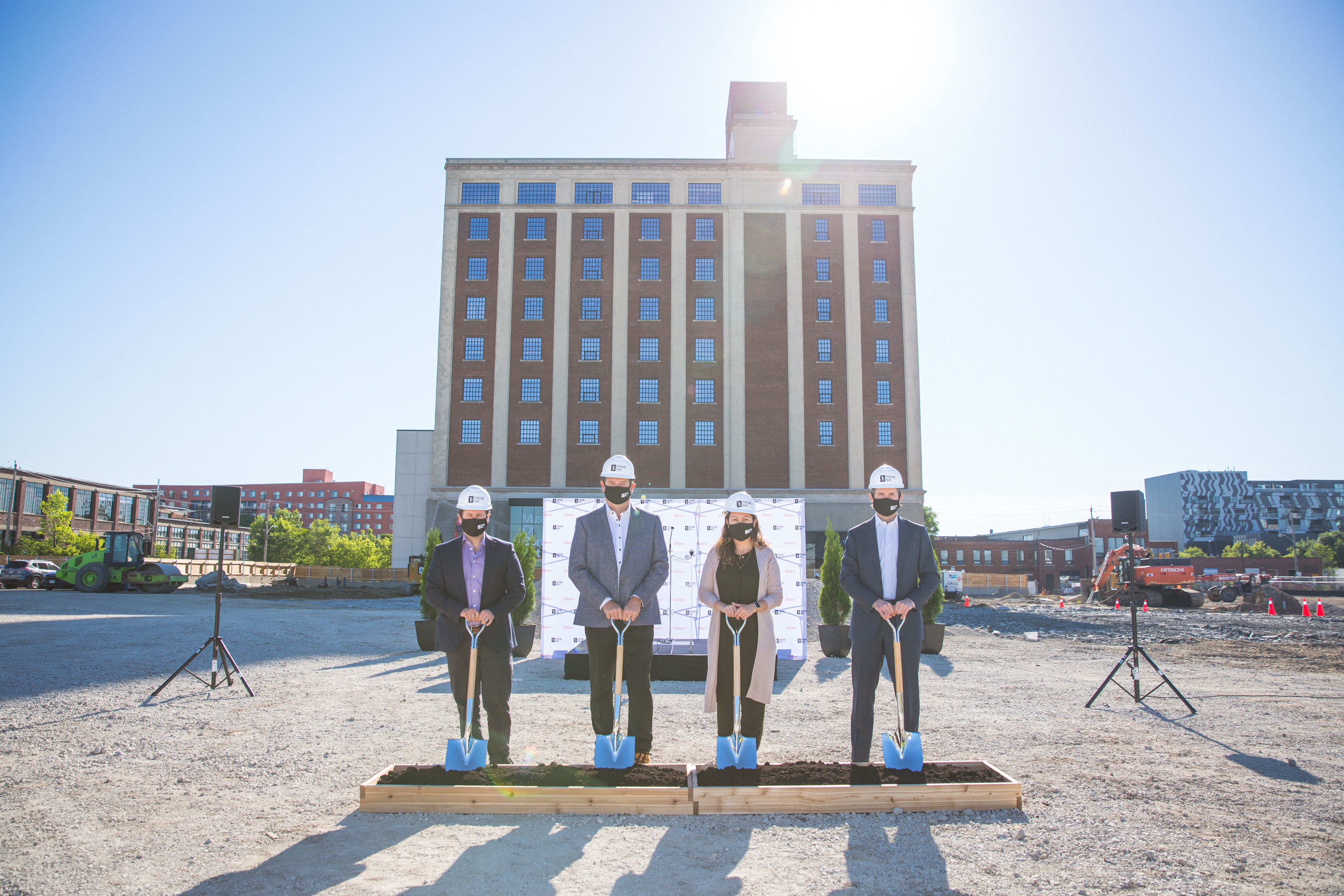 Four people with shovels, breaking ground on a new development