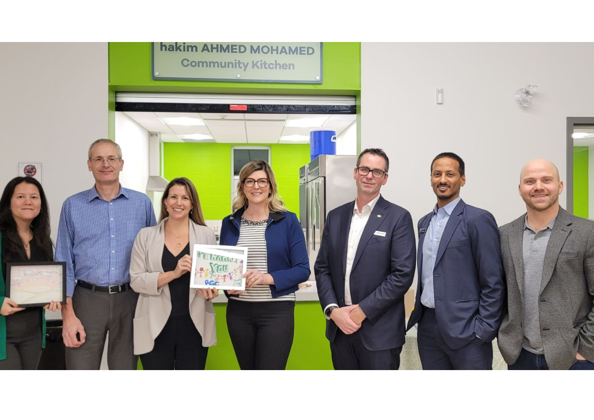 A group of people standing together in front of the Hakim Ahmed Mohamed Community Kitchen entrance.