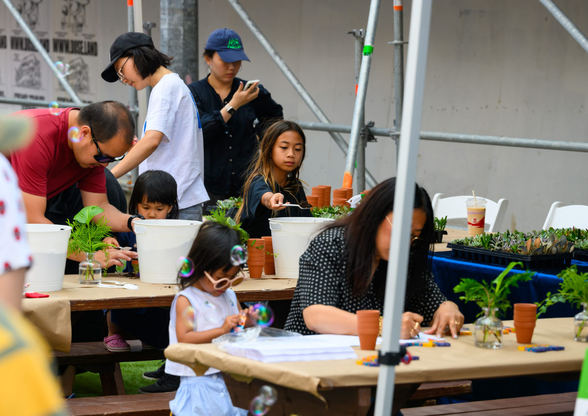People seated at tables participating in an outdoor planting activity,